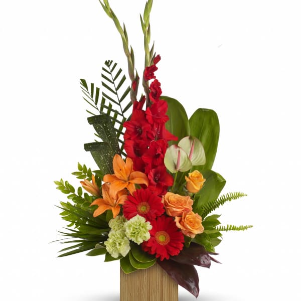 Tropical floral arrangement with red, orange, and green blooms in a wooden container