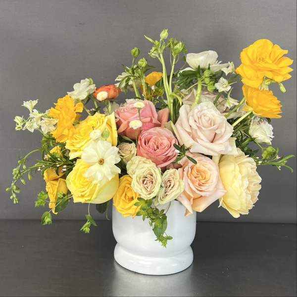 Mixed bouquet of roses and yellow blooms in a white vase