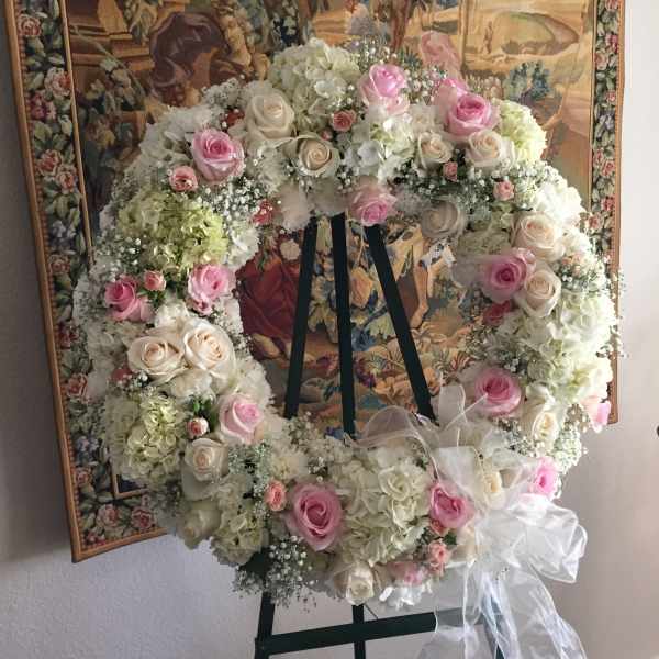 Large floral wreath of pink and white roses on a black stand