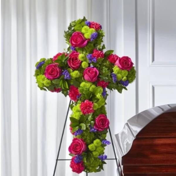 Cross-shaped floral tribute with pink roses and bright mixed blooms