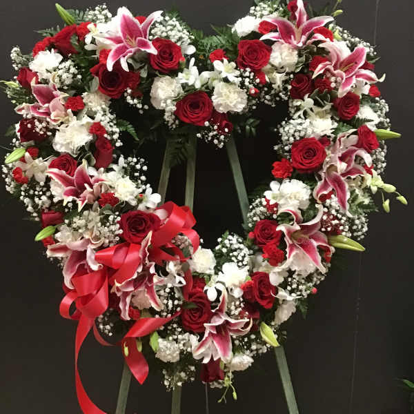 Heart-shaped floral wreath with red roses, pink lilies, and white flowers