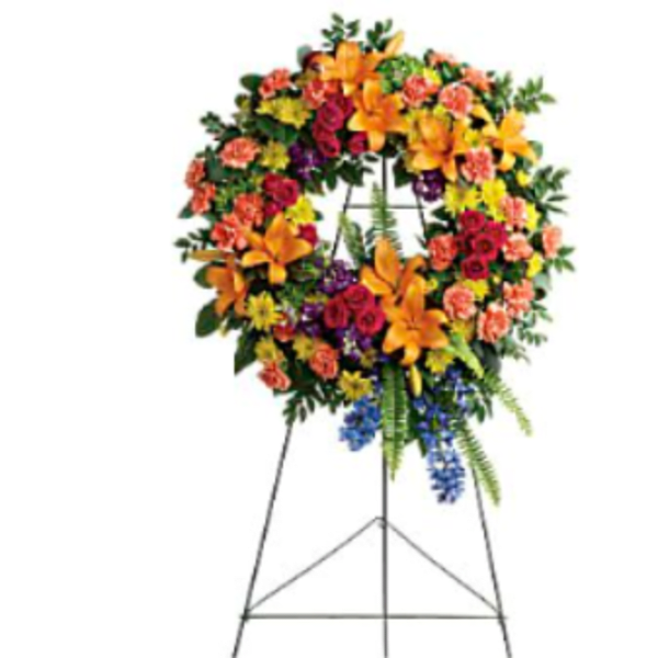 Large standing floral wreath on an easel with orange, red, yellow, and blue flowers