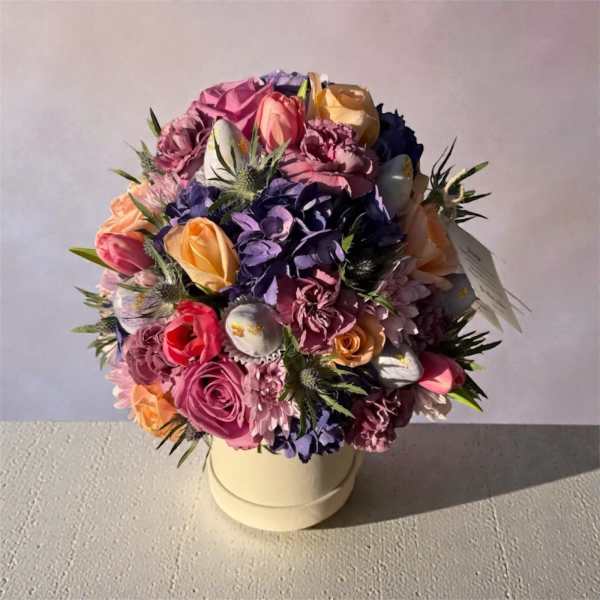 Round bouquet of multicolored roses and carnations in a cream box