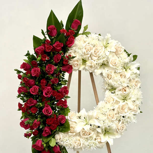 Two floral wreaths on easels, one red and one white.