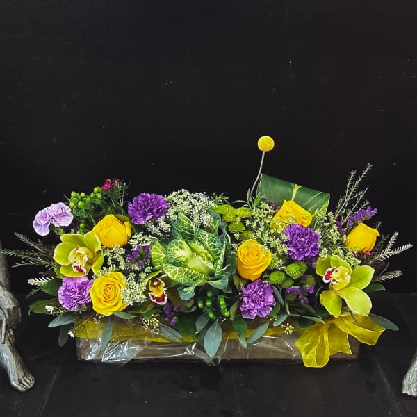 Bright yellow and purple floral arrangement in a low rectangular container