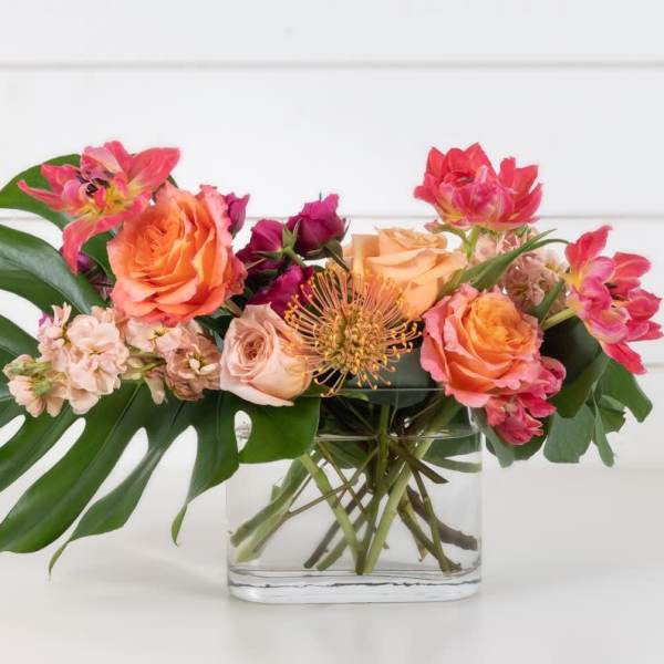 Mixed bouquet of pink and orange flowers in a clear glass vase