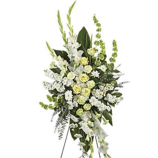 Tall white and pale yellow funeral spray on a stand