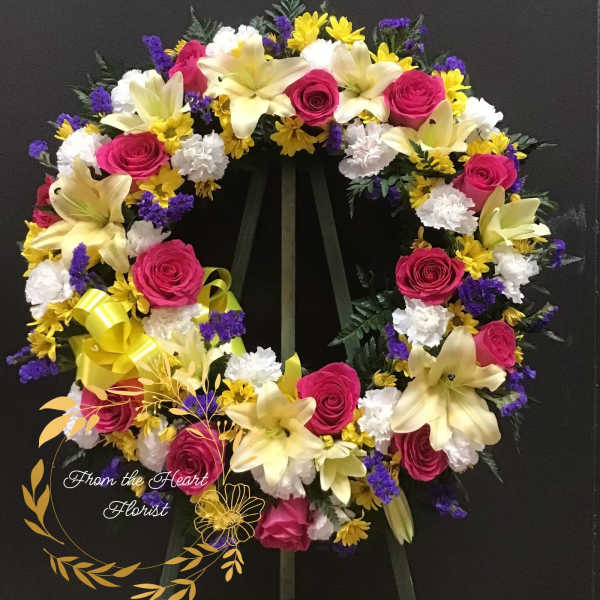 Heart-shaped floral wreath with pink roses, lilies, and yellow daisies