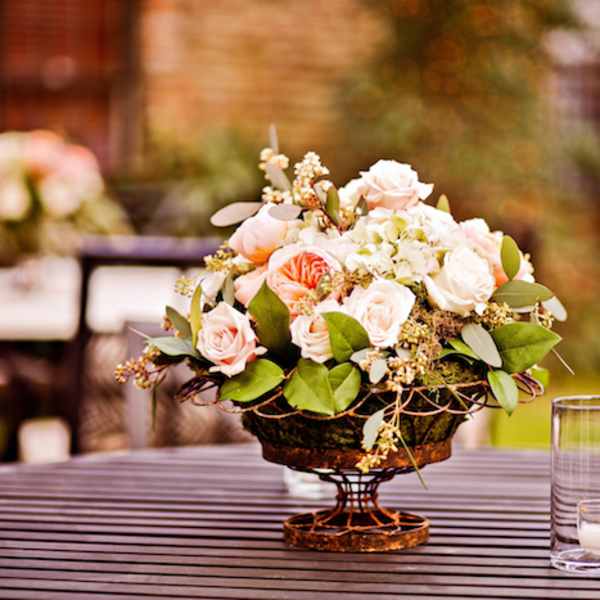 Low floral centerpiece with pale pink roses in a decorative bowl on a table