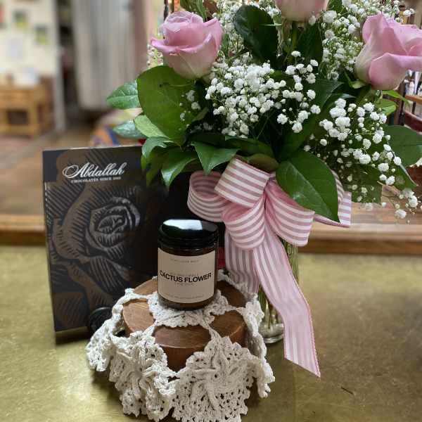 Pink roses with baby's breath in a glass vase, with chocolates and a candle