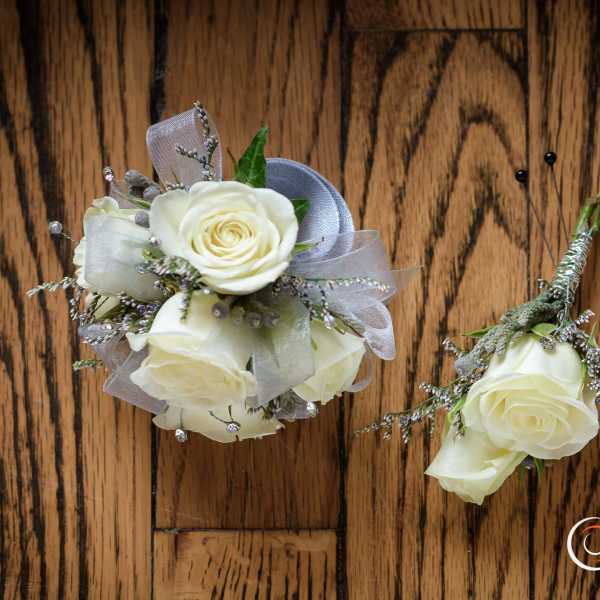 White rose boutonniere and small matching floral cluster on a wood surface
