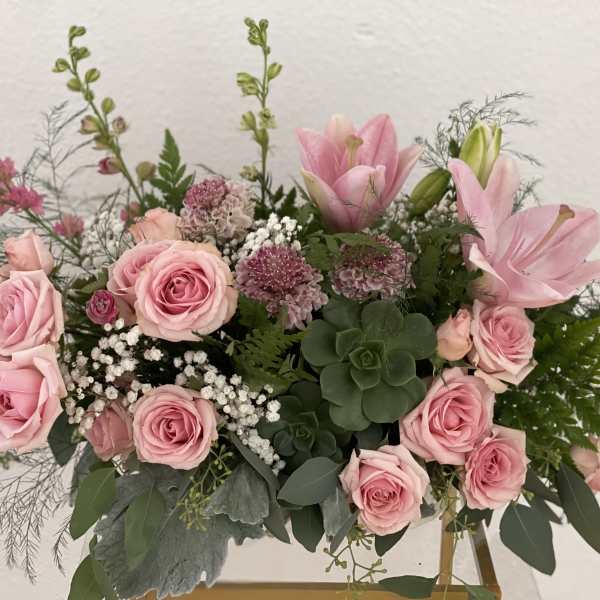 Pink roses and lilies arranged in a low vase with greenery