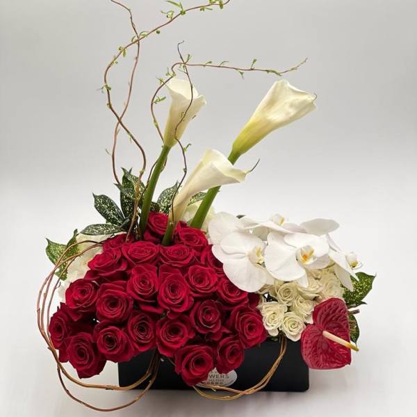 Red roses with white calla lilies and orchids in a black container