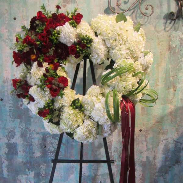 Heart-shaped floral wreath with red and white flowers on an easel