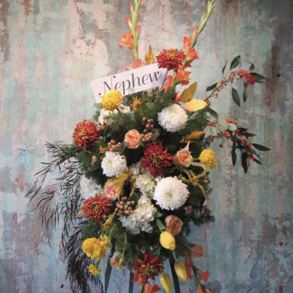 Standing floral spray with orange, yellow, white, and red blooms