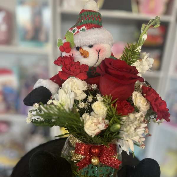 Snowman figurine in a holiday flower arrangement with red and white blooms