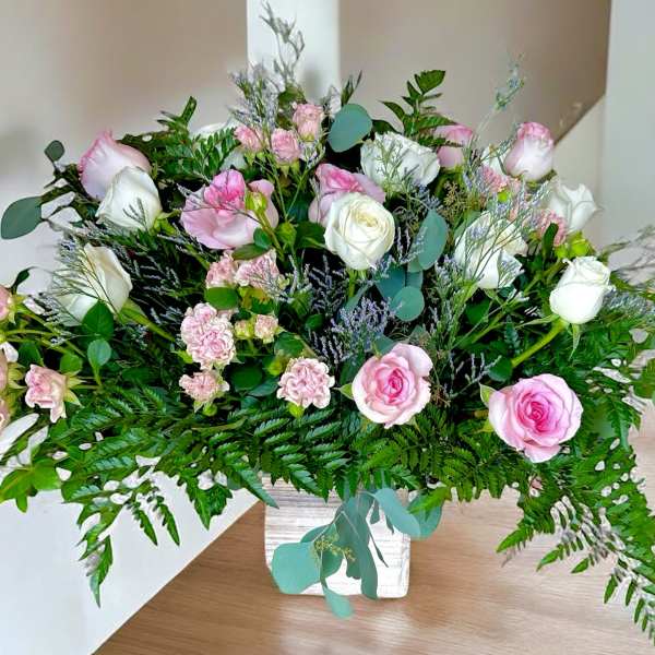 Pink and white rose arrangement in a white vase
