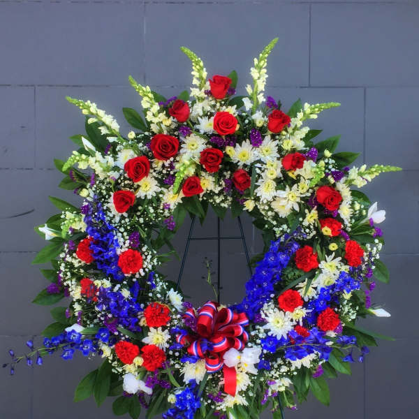 Large circular floral wreath on a stand with red, white, blue, and purple flowers