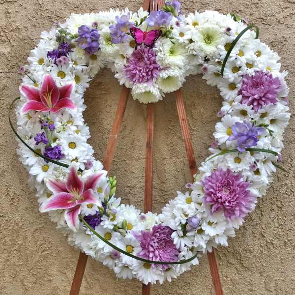 Heart-shaped floral wreath with white daisies, pink lilies, and purple blooms