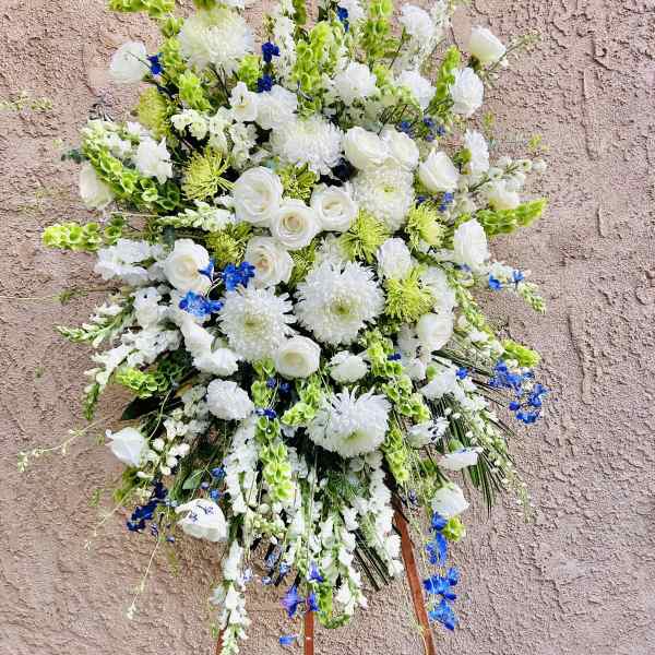 Large white floral standing spray with blue accents on an easel