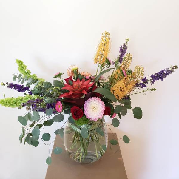 Mixed bouquet in a clear glass vase with red, pink, purple, and yellow blooms