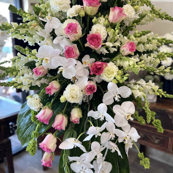 Tall floral arrangement with pink roses, white orchids, and white carnations