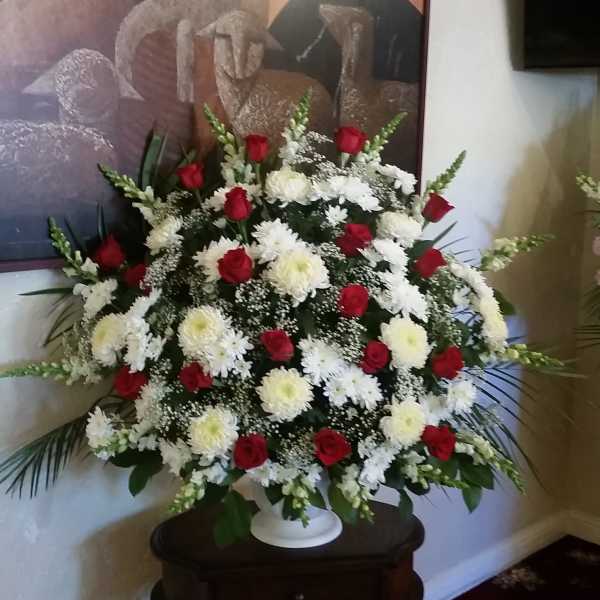 Large standing arrangement of red roses and white chrysanthemums in a white urn
