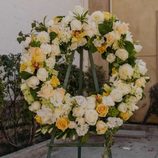 Large floral wreath of white and yellow flowers on a stand