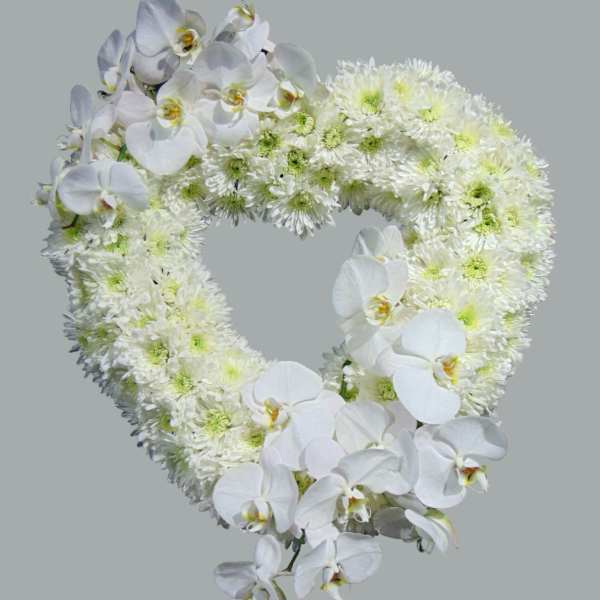Heart-shaped wreath of white orchids and chrysanthemums on a gray background