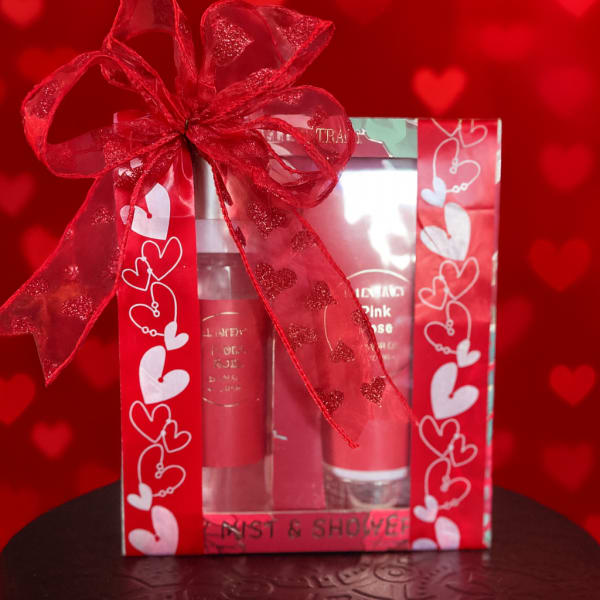 Gift box with red heart ribbon and two pink cosmetic tubes