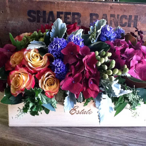 Mixed floral arrangement in a wooden box with roses and hydrangeas