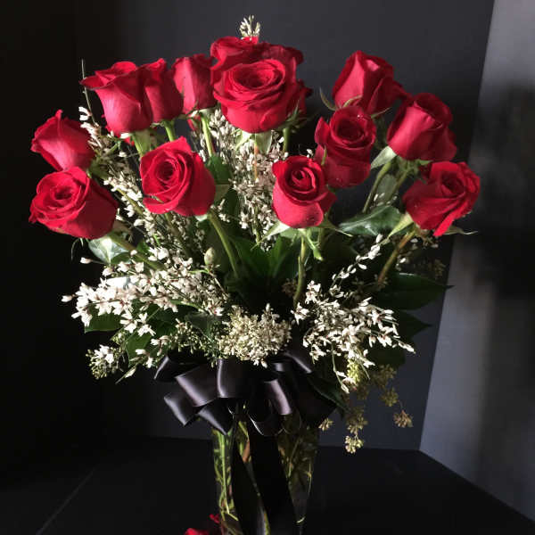 Bouquet of red roses in a glass vase with a black ribbon