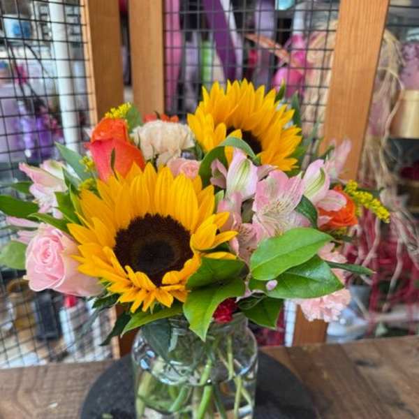 Sunflowers and pink mixed flowers arranged in a glass vase