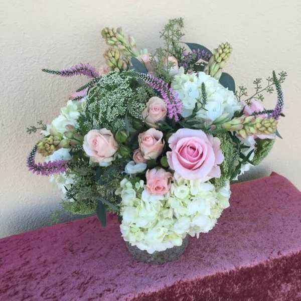 Pink roses and white hydrangeas arranged in a low vase.