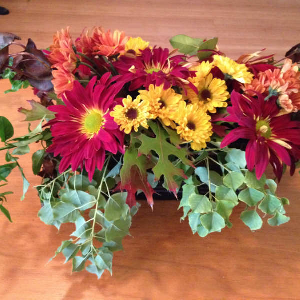 Low floral arrangement with magenta and yellow daisies on a table