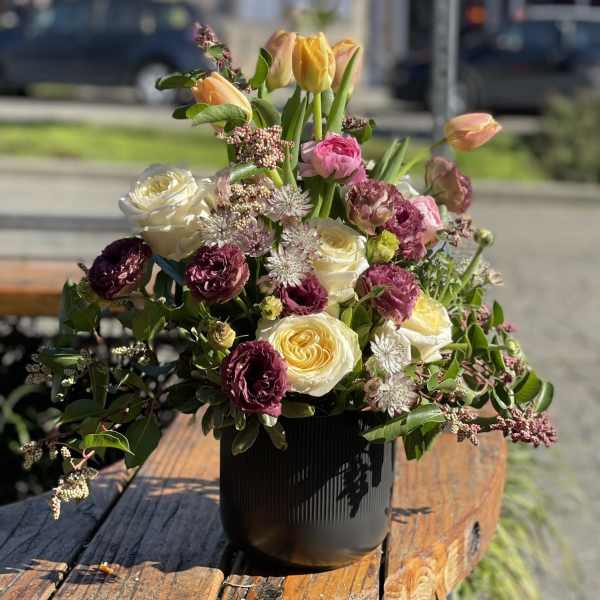 Mixed bouquet of roses, tulips, and astrantia in a black vase