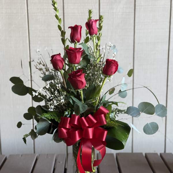 Red roses in a clear glass vase with a red ribbon