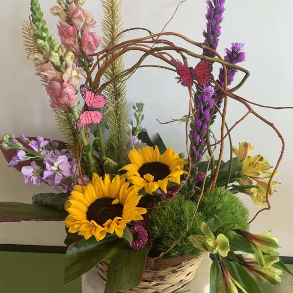 Basket arrangement with sunflowers, snapdragons, and purple flowers