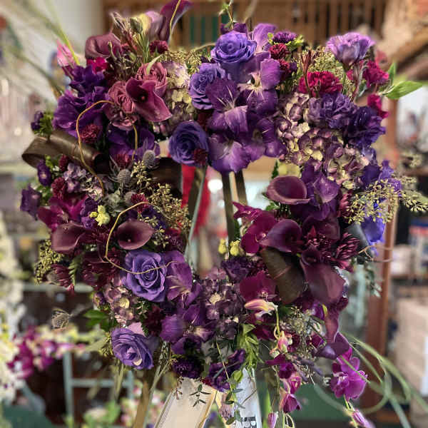 Purple floral heart wreath on an easel with ribbon banners