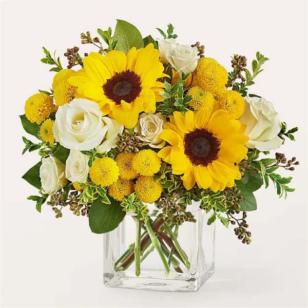 Yellow sunflowers and white roses in a clear glass vase
