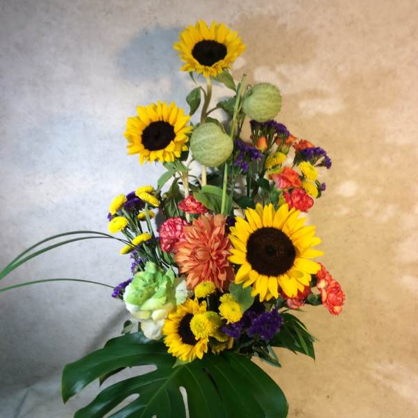 Tall mixed bouquet with sunflowers in a glass vase
