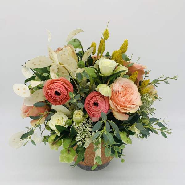 Peach and coral roses with white blooms arranged in a decorative ceramic pot.