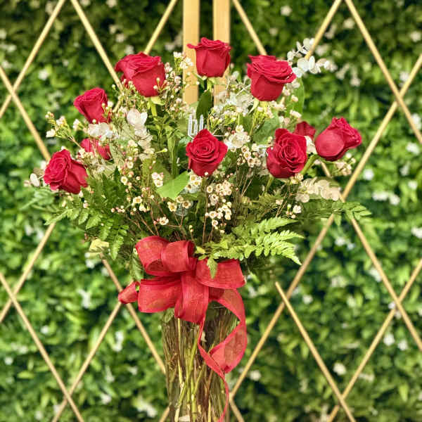 Red roses arranged in a clear glass vase with a red ribbon