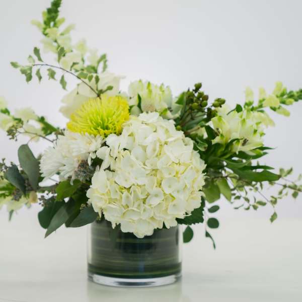 White and pale yellow floral arrangement in a glass vase