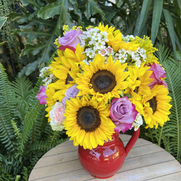 Bouquet of sunflowers and roses in a red pitcher vase