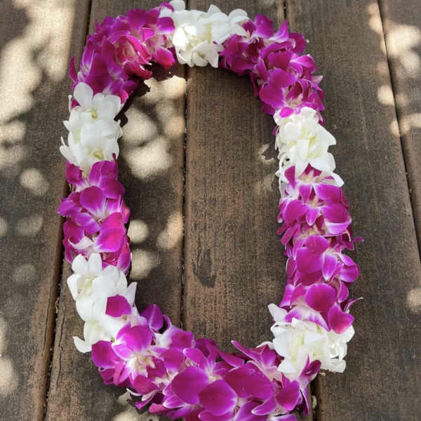 Pink and white orchid lei on a wooden surface