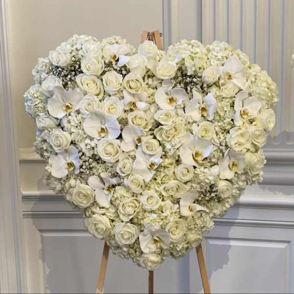 Heart-shaped white floral arrangement on an easel