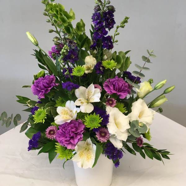 Mixed bouquet in a white vase with purple, white, and green flowers