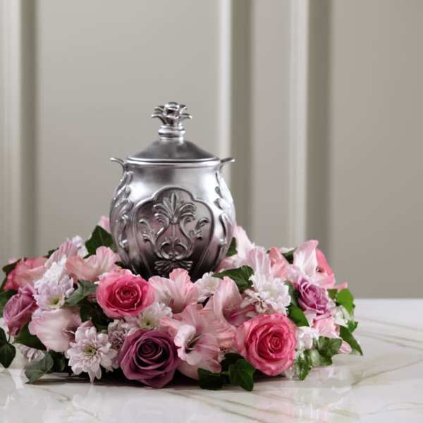 Pink floral arrangement around a silver urn