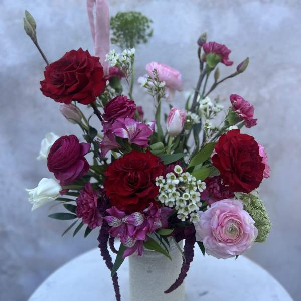 Mixed bouquet of red, pink, and white flowers in a white vase
